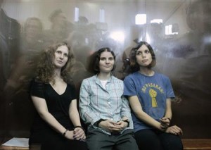 Members of the female punk band "Pussy Riot" sit in a glass-walled cage after a court hearing in Moscow